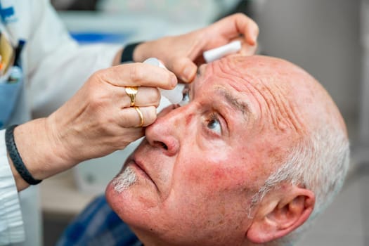 Ophthalmologist pouring drops to dilate the pupil to a man during a glaucoma examination test