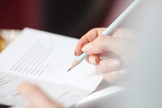 woman's hand writing in a notebook booklet entry