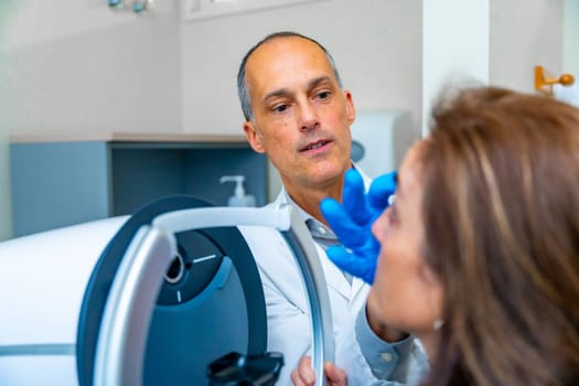 Ophthalmologist checking the eye of a woman during treatment for glaucoma using innovative laser machine
