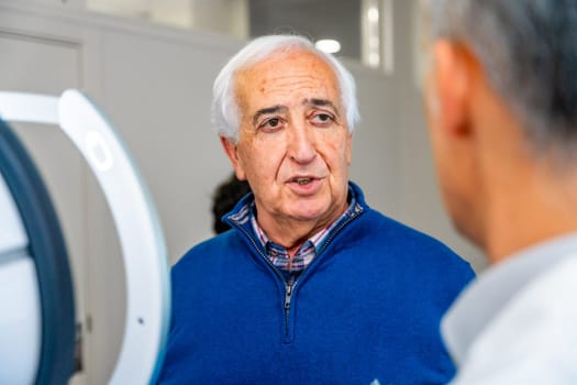 Satisfied senior man talking to an ophthalmologist in the clinic after receive an innovative glaucoma treatment with laser