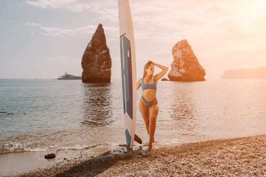 Close up shot of beautiful young caucasian woman with black hair and freckles looking at camera and smiling. Cute woman portrait in a pink bikini posing on a volcanic rock high above the sea