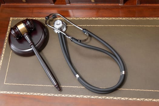 A close-up of a judge's gavel and a black stethoscope on top of a legal book, signifying the intersection of law and medicine