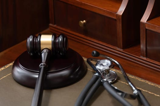 A close-up of a judge's gavel and a black stethoscope on top of a legal book, signifying the intersection of law and medicine