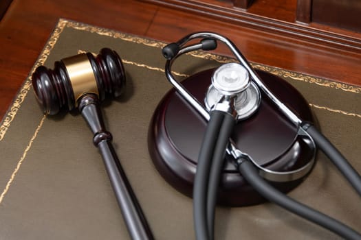 A close-up of a judge's gavel and a black stethoscope on top of a legal book, signifying the intersection of law and medicine