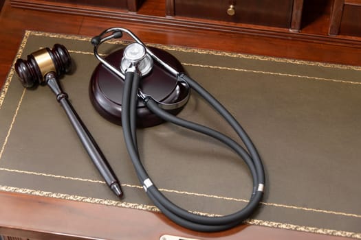 A close-up of a judge's gavel and a black stethoscope on top of a legal book, signifying the intersection of law and medicine