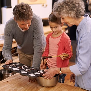 Child, grandparents and baking with cupcakes, kitchen and bonding together. Mature woman, smile and girl with happiness, love and learning at home with grandmother for childhood memories and family.