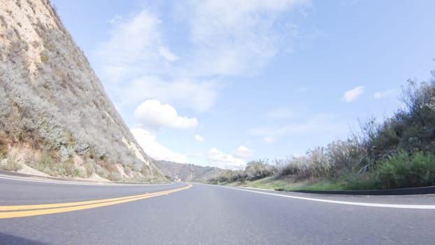 Vehicle is cruising along the Cuyama Highway under the bright sun. The surrounding landscape is illuminated by the radiant sunshine, creating a picturesque and inviting scene as the car travels through this captivating area.