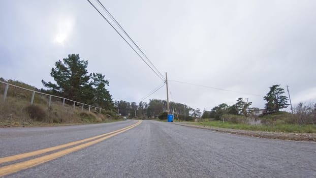 Vehicle navigates the streets of Morro Bay, California, during a cloudy winter day. The atmosphere is moody and serene as the overcast sky casts a soft light on the charming buildings and quiet streets of this coastal town.