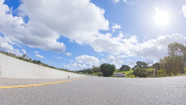 On a clear winter day, a car smoothly travels along Highway 101 near Santa Maria, California, under a brilliant blue sky, surrounded by a blend of greenery and golden hues.