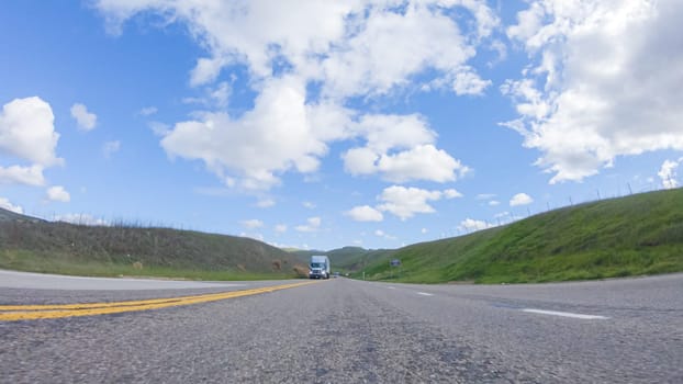 On a clear winter day, a car smoothly travels along Highway 101 near Santa Maria, California, under a brilliant blue sky, surrounded by a blend of greenery and golden hues.