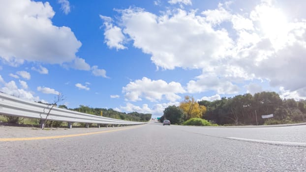 On a clear winter day, a car smoothly travels along Highway 101 near Santa Maria, California, under a brilliant blue sky, surrounded by a blend of greenery and golden hues.