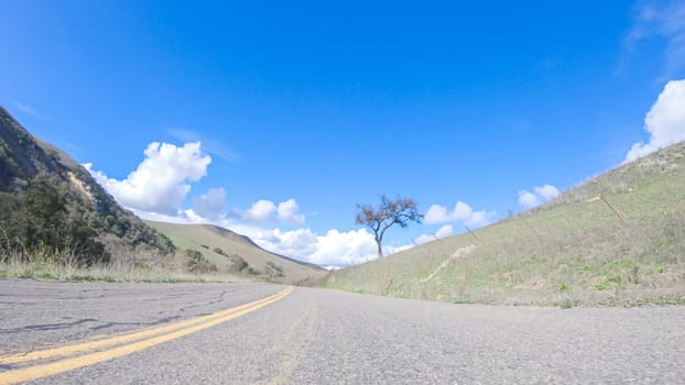 Vehicle is cruising along the Cuyama Highway under the bright sun. The surrounding landscape is illuminated by the radiant sunshine, creating a picturesque and inviting scene as the car travels through this captivating area.