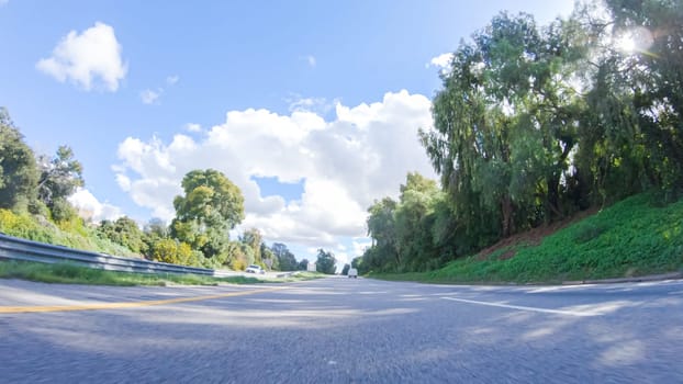 On a clear winter day, a car smoothly travels along Highway 101 near Santa Maria, California, under a brilliant blue sky, surrounded by a blend of greenery and golden hues.