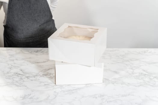 The freshly baked bundt cakes are carefully nestled into white paper boxes, preparing them for secure transportation while maintaining their delectable appearance.