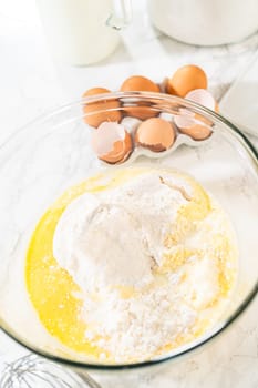 Combining ingredients within a glass bowl, skillfully stirring with a whisk to prepare a delicious vanilla bundt cake.