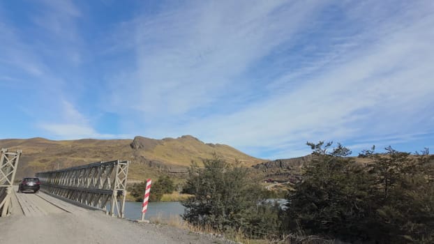 A car crosses a bridge in a mountainous region.