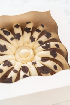Packaging the freshly baked pumpkin bundt cake into a white paper box for gifting.