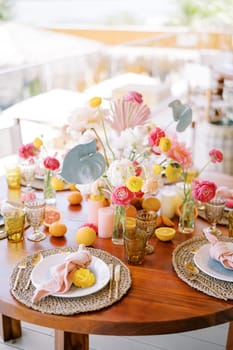 Plates with knotted napkins on mats stand on a festive table with colorful flowers. High quality photo