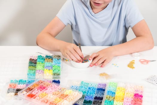 Little girl enjoys crafting colorful bracelets with vibrant clay beads set.