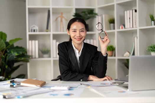 Young business woman asian or employee accounting bookkeeping documents checking financial data or marketing report working in office with laptop. Paperwork management.