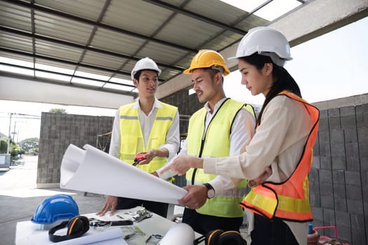 team of civil engineers and architects wearing hard hats Currently in a brainstorming meeting holding project plans to plan a building construction project..