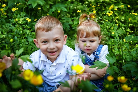 Cute kids in flowers in nature. Funny Boy and girl in grass. A good environment means Healthy, happy children