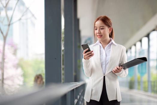 Asian business woman beautiful with smart phone and document file, asian woman with smartphone walking go to work. Preparation for the working day.
