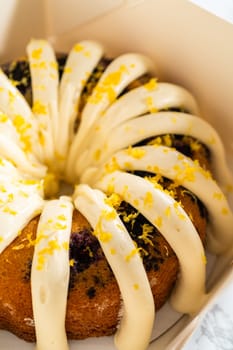 The freshly baked bundt cakes are carefully nestled into white paper boxes, preparing them for secure transportation while maintaining their delectable appearance.