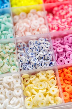 Assorted clay bead boxes neatly arranged on a white table, awaiting a creative kids' craft project.