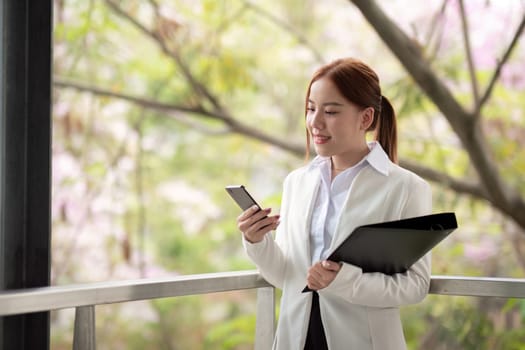 Asian business woman beautiful with smart phone and document file, asian woman with smartphone walking go to work. Preparation for the working day.