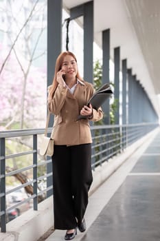 Asian business woman beautiful with smart phone and document file, asian woman with smartphone walking go to work. Preparation for the working day.