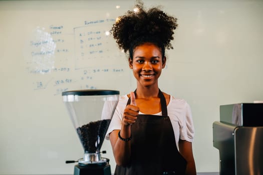 Portrait of a confident black woman owner standing at cafe counter. Successful businesswoman in uniform providing excellent service smiling with satisfaction. Inside a small business cafe