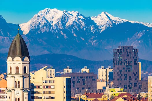 Ljubljana, Slovenia: View of modern residential buildings and Church of St. Joseph with picturesque snowy Alps in the background