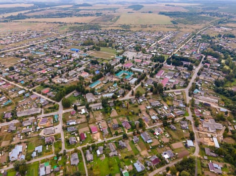 Aerial view of dwelling houses between roadways and meadows with trees in region of Kirov Russia