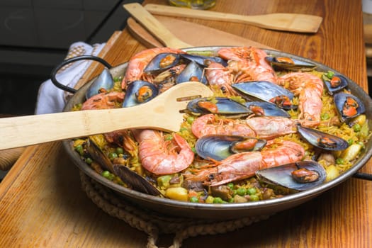 Wooden spoon resting on a pan of hearty shrimp paella, typical Spanish cuisine, typical Spanish cuisine, Majorca, Balearic Islands, Spain,