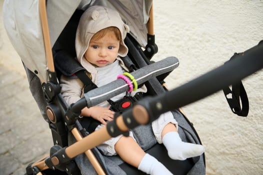 A cute baby boy in baby pram, stroller, pushchair during a family walk outdoors. People. Lifestyle. Maternity leave. Parenthood and motherhood. Childbirth. Childcare concept. Children transportation