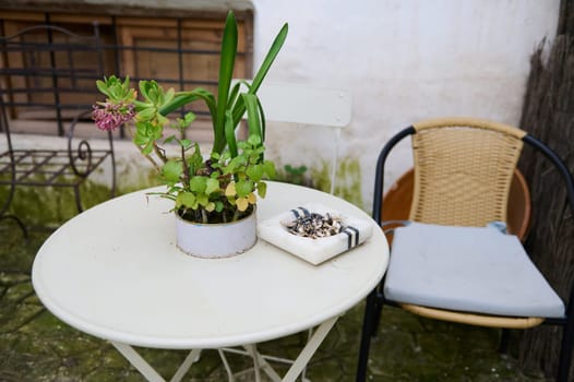 Still life of a white table with chair in the garden. Ashtray with cigarette butts on the table. The concept of lung diseases. Lung cancer awareness campaign
