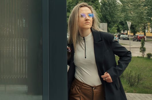 A woman wearing a black coat and blue glasses.