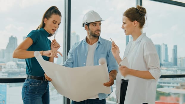 Professional architect engineer team talking, sharing, brainstorming about design while manager hold at project plan. Young architect holding plan while manager listen and point at plan. Tracery