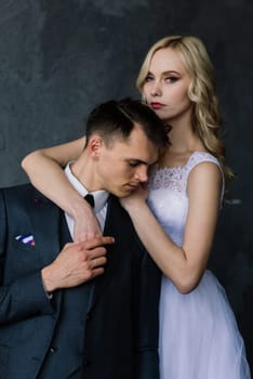 Cute wedding couple in the interior of a classic studio decorated. They kiss and hug each other.