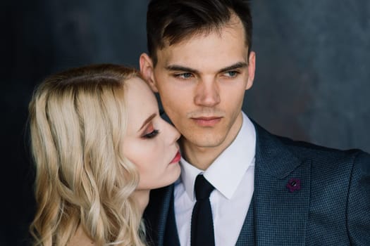 Cute wedding couple in the interior of a classic studio. They kiss and hug each other.