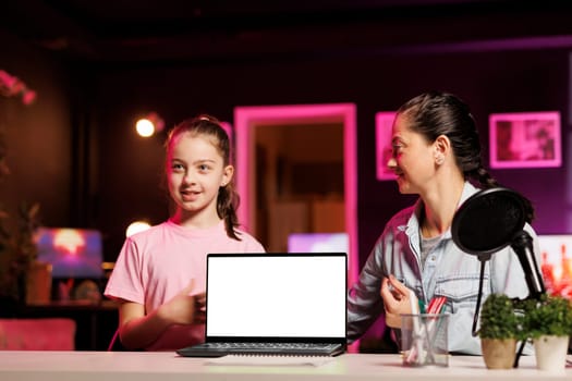 Child media star filming video about best mockup laptops launched this year. Cute girl tech content creator recording isolated screen notebook review, assessing build quality and performance