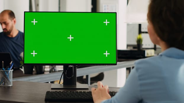 Manager working with isolated greenscreen on computer at workstation, looking at chromakey display with mockup template on desk. Businesswoman using pc in coworking space.