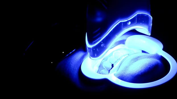 High-contrast image of a helmet illuminated with intense neon blue light, creating a futuristic ambiance
