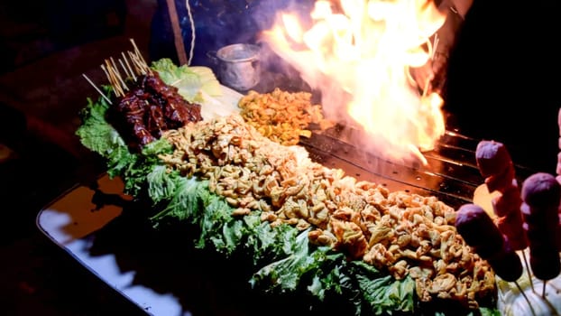 Vibrant street food stall with dramatic flames engulfing a wok, cooking a variety of dishes after dark