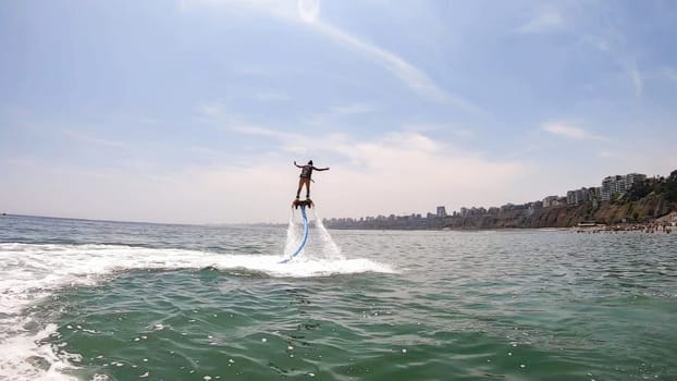 Exhilarating scene of a person using a water-propelled jet pack on a sunny day by the beach