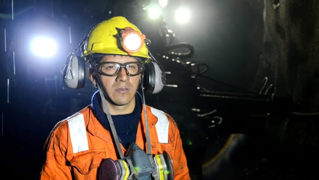 Cerro de Pasco, Peru - July 14th 2017 : Portrait of a focused miner wearing a headlamp and safety gear in a dimly lit underground mine