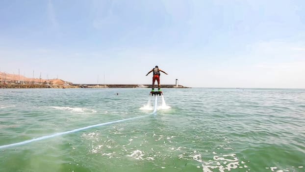Adventurous male flyboarder hovering over the sea with clear skies in the background
