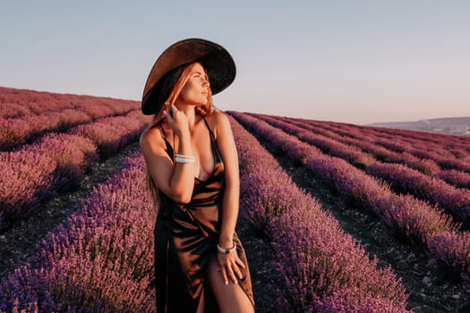 Close up portrait of young beautiful woman in a white dress and a hat is walking in the lavender field and smelling lavender bouquet.