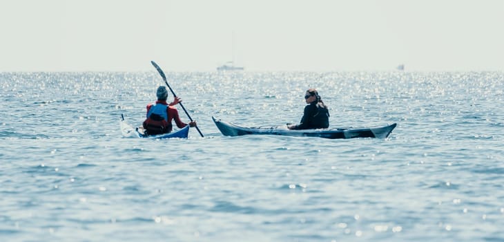 Happy smiling woman in kayak on ocean, paddling with wooden oar. Calm sea water and horizon in background